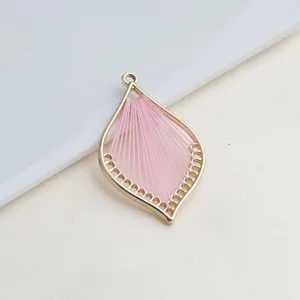 Close-up van een handgemaakte DIY sieraden roze draad geweven blad bedel hanger detail.