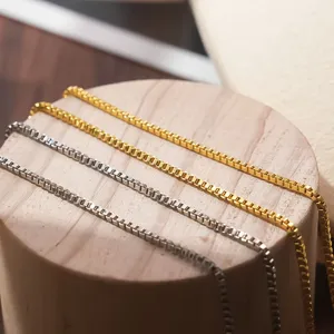 Detailopname van roestvrijstalen boxkettingen in goud en zilver, fijne schakels.