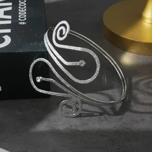 Gedetailleerde close-up van de zilveren metalen armspang met sprankelende kristallen.