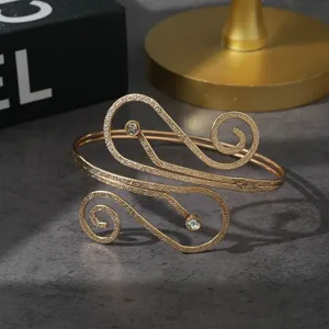Overdreven gouden metalen armband met sprankelende strass-details in minimalistische stijl.