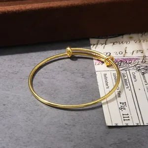 Gold tone adjustable wire bangle bracelet detail, minimalist metal cuff design for women wear.