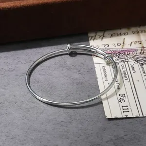 Adjustable silver wire bangle detail shot, minimalist metal bracelet close-up view accessory.