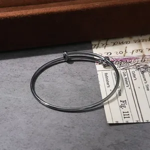Adjustable metal coil bracelet detail shot, sleek dark tone versatile fashion wristband.