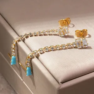 Vergulde lange bungelende oorbellen met fonkelende kubieke zirkonia stenen en blauwe accenten.