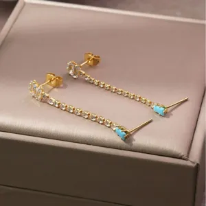 Vergulde lange oorbellen met sprankelende zirkonia stenen en elegante turkooizen accenten.