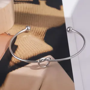 Primer plano muy detallado del elegante brazalete rigido de acero titanio con nudo de amor.