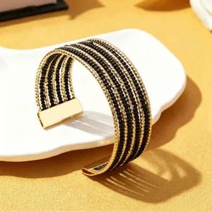 Close-up detail van een stijlvolle meerlaagse kraal armband in zwart-gouden afwerking.