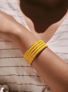 Gedetailleerde opname van bohemian meerlaagse gele kralen armband met gouden metalen staven.
