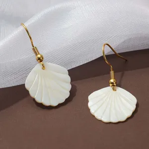 Gedetailleerd uitzicht op witte schelp oorbellen met vergulde haken voor de zomer.