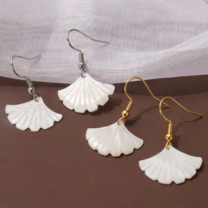 Close-up van witte schelp ginkgo blad oorbellen detail, minimalistische natuurlijke stijl.