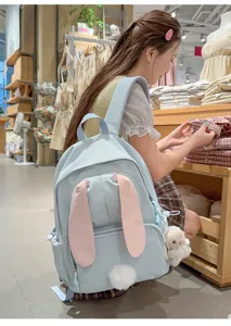 Detailopname van de schattige lichtblauwe rugzak met konijnenoren gedragen in een winkel.