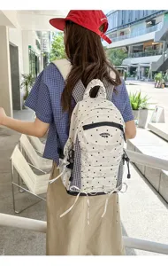 Detailopname van een Japanse stijl geplooide stippenrugzak met ruitaccenten en ster.