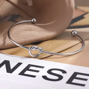 Primer plano de una pulsera rígida minimalista de acero de titanio con un nudo elegante.