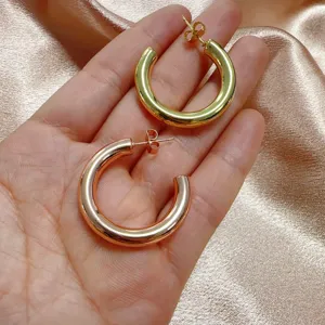 Gedetailleerd overzicht van dikke créolen met een gladde metalen afwerking en twee kleuren.