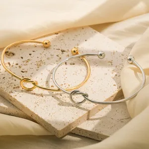 Gouden en zilveren open metalen armbanden met chic knoopdesign, elegante dagelijkse sieraden.