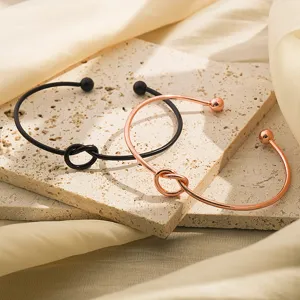 Elegante open metalen armband met stijlvol knoopontwerp en baluiteinden in twee kleuren.