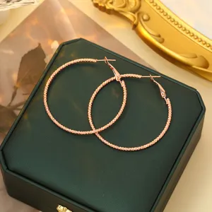 Detailopname van chic roségouden creolen met getextureerd oppervlak en glanzende afwerking.