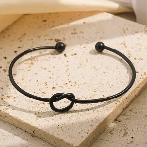 Prachtige zwarte metalen knoop manchet armband met open ontwerp en chique baliteinden.