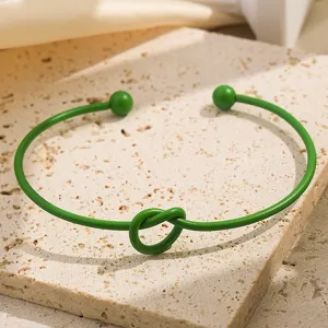 Groene open metalen armband met knoopontwerp en baluiteinden, stijlvolle minimalistische sieraden.