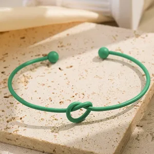 Groene metalen knoop open armband, elegante detailfoto met uniek getwist ontwerp.