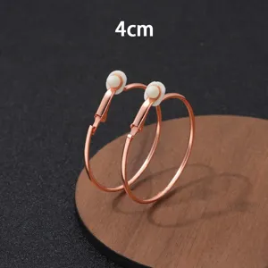 Close-up detail van 4cm roségouden creolen clip-oorringen, eenvoudig metalen design voor dames.