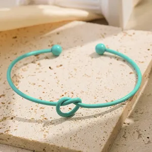 Detailopname van de mintgroene metalen open armband met knoopontwerp en bal-einden voor stijl.