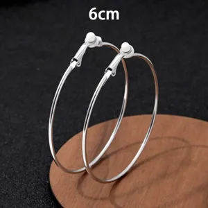 Gedetailleerd overzicht van grote zilveren creoolse oorbellen van 6cm, met gepolijste metaalstructuur.