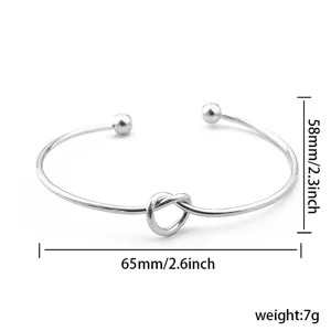 Zilverkleurige metalen open armband met knoop en baliteinden, elegant minimalistisch sieraad.