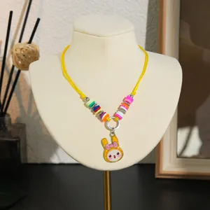 Gedetailleerd overzicht van kleurrijke kleikralen kinderketting met schattige gele konijnenhanger.
