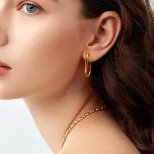 Close-up van minimalistische geometrische vergulde messing creolen gedragen, elegante stijl.