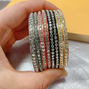 Gedetailleerd overzicht van gestapelde kristallen strass metalen armbanden in kleuren.