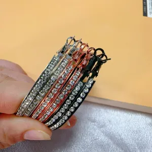Detailopname van meerkleurige metalen strass-oorringen in zilver, roségoud en zwart voor dames.
