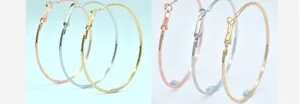 Gedetailleerde close-up van grote metalen oorringen in goud, zilver en roségoud.