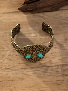 Gedetailleerd overzicht van brede vintage bronskleurige armband met takkenmotief en turkoois.