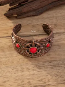 Gedetailleerd overzicht van de brede vintage koperen armband met rode stenen.