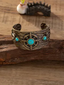 Gedetailleerde close-up van vintage bronzen manchetarmband met turkoois stenen.