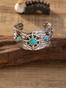 Gedetailleerde close-up van brede vintage zilveren metalen manchetarmband met stenen.