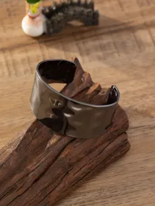 Gedetailleerde close-up van de brede metalen manchetarmband met gehamerde textuur en retro look.