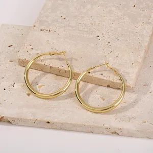 Detailopname van grote gouden oorbellen, met weergave van het gepolijste gladde metalen oppervlak.