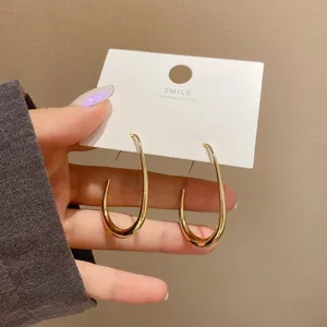 Stijlvolle vergulde gladde druppel oorbellen detail op witte kaart mode sieraden.