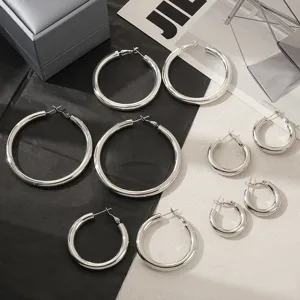 Detailaufnahme van zilveren oorbellen in verschillende maten met gladde metalen afwerking.