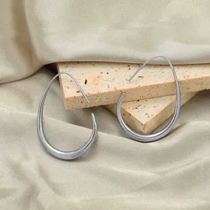 Close-up detail van zilveren druppel-oorringen op gestructureerde stenen rekwisieten en zijde.
