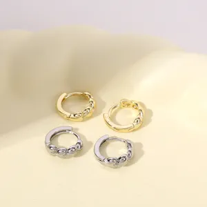 Chique getwiste kleine creoolse oorbellen in goud en zilver, gedetailleerde close-up.