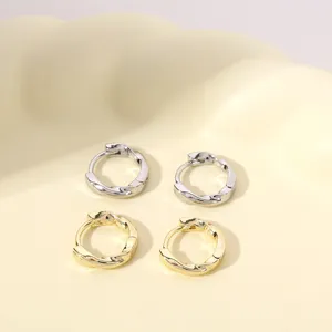 Detailopname van gedraaide metalen oorbellen in goud en zilver, stijlvolle dagelijkse sieraden.
