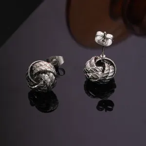 Detalle en primer plano de pendientes de tuerca geométricos de metal plateado con acabado brillante.