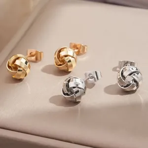 Exquisitos pendientes de tuerca con nudo metálico en oro y plata con diseño espiral geométrico.