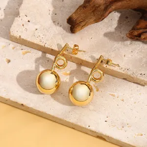 Gedetailleerd close-up van stijlvolle Franse luxe gouden metalen bolvormige oorbellen.