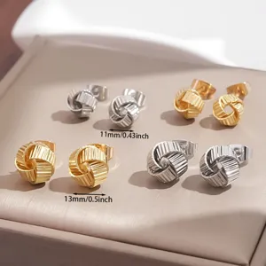 Primer plano de elegantes pendientes de botón geométricos de nudo en oro y plata con tamaños.