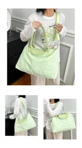 Detail view of the light green nylon tote bag featuring star embroidery and leather handles.