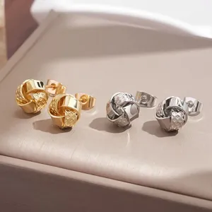 Elegantes pendientes de botón de nudo metálico en acabado dorado y plateado, diseño elegante.